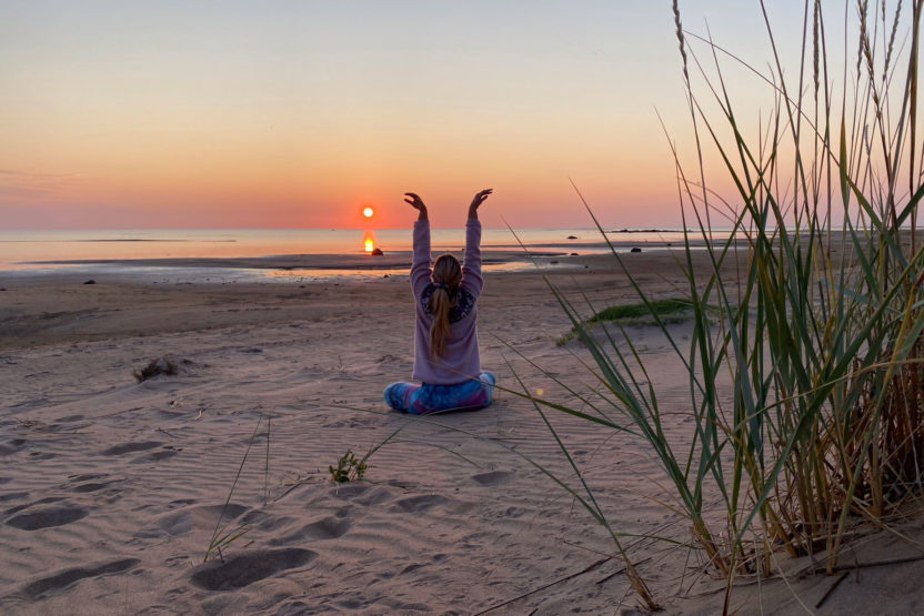 nainen jogaa hiekkarannalla auringonlaskussa