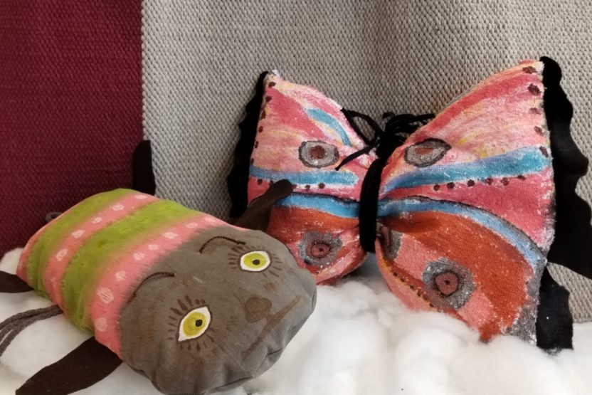 Kaksi eläinpehmoa, toinen esittää toukkaa ja toinen perhosta.