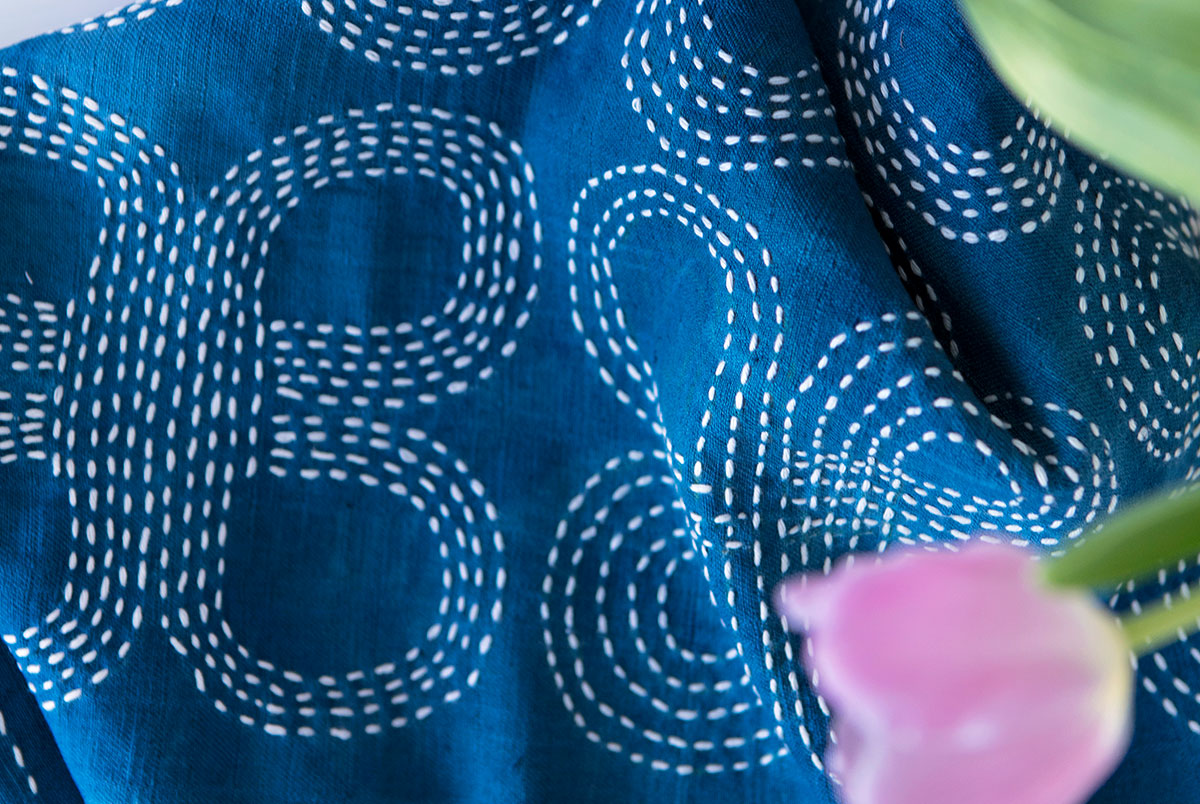 Sashiko-kirjonnalla kuvioitu liina, kuvioina hannunvaakunakuvioita, valkoinen kirjonta sinisellä pohjalla.