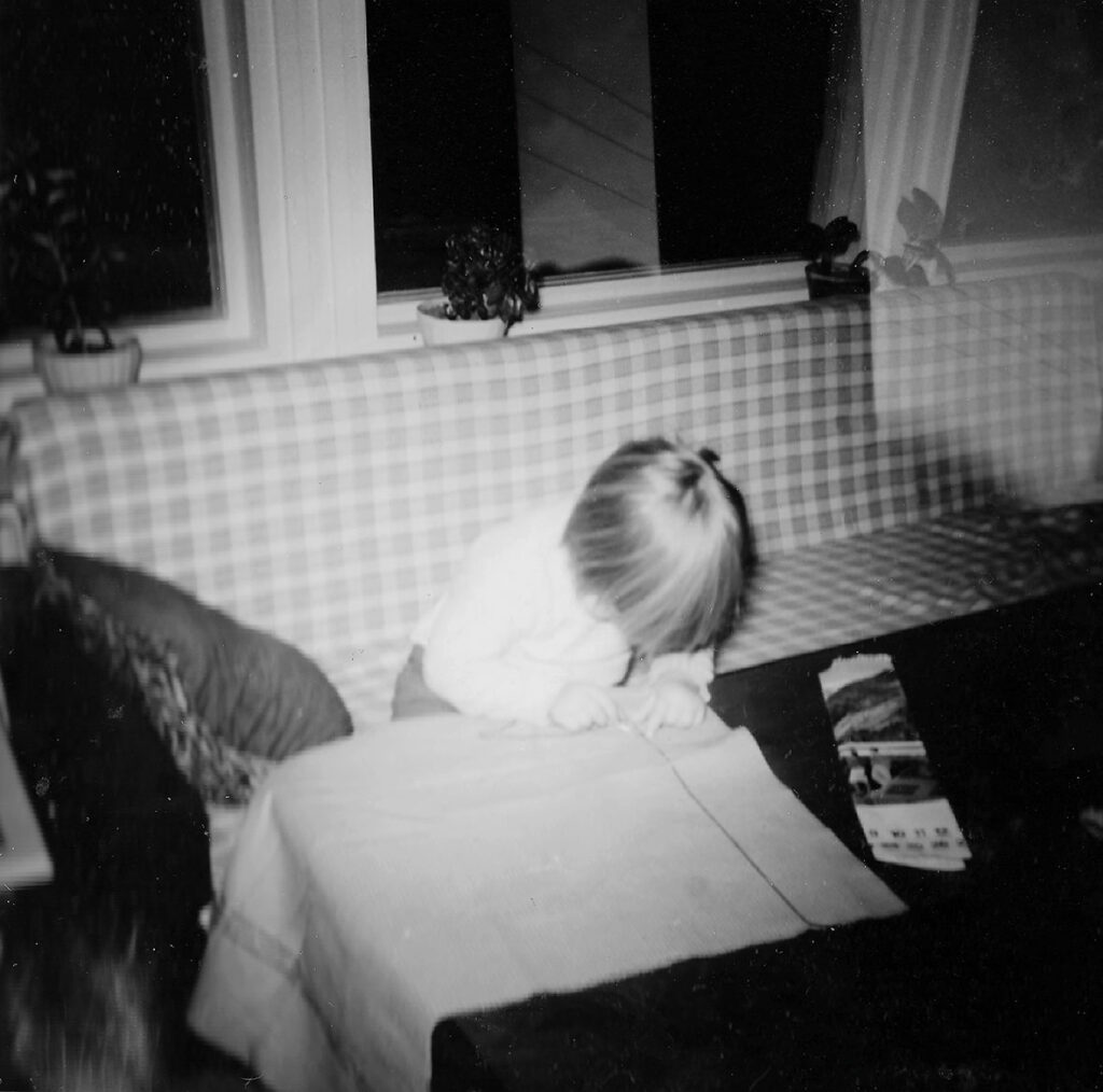 Ail Aho lapsena leikkaamassa kangasta, mustavalkokuva 1960-luvulta.