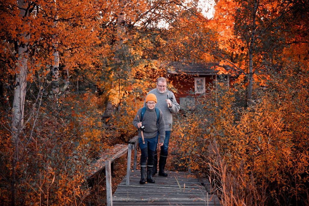 Poika ja isoisä laiturilla päällään harmaan luotolaisvillapaidat, taustalla oranssilehtiset ruskapuut.