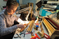 15-vuotias Petu Partanen soitinkorjauspöydän ääressä tekemässä korjaustyötä, pöydällä haitarin osia ja työkaluja.