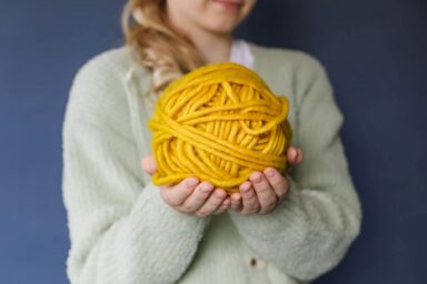 nainen keltainen lankakerä kädessä