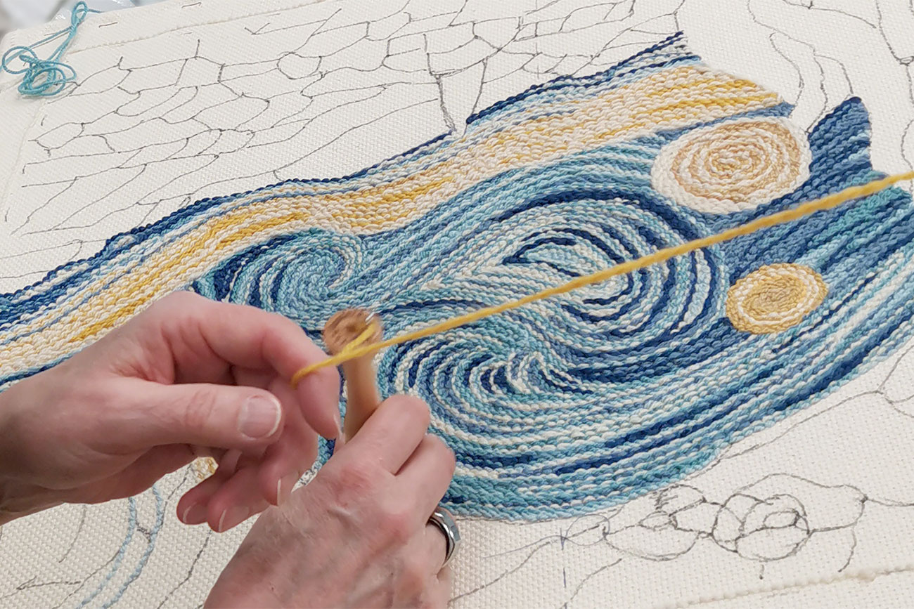 Nainen tuftaa kangasta Vincent van Goghin taulun pohjalta.