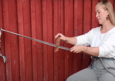 Nuori nainen kutoo pirtanauhaa.