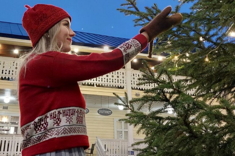 Tonttutyttö koristelee joulukuusta Taitokorttelin pihalla.