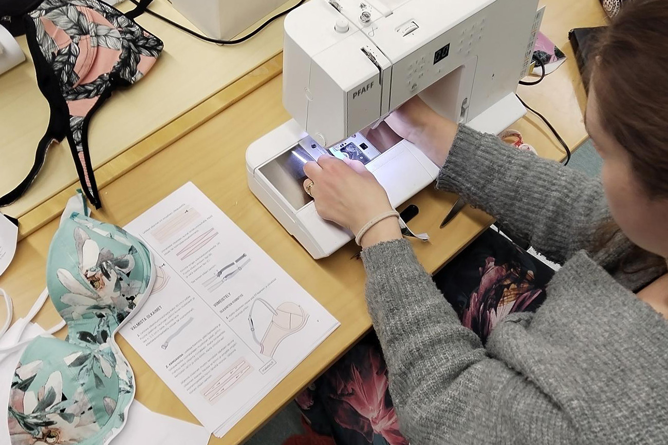 Kurssilainen ompelee rintaliivejä.