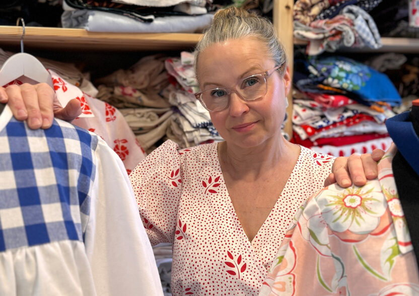 Maria-Söderström seisoo kangashyllyn edessä, kahden mallinukketorson välissä.