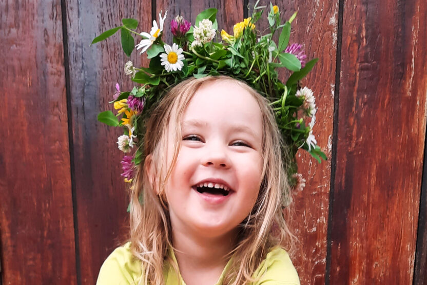 Kuvassa lapsi kukkaseppele päässään.