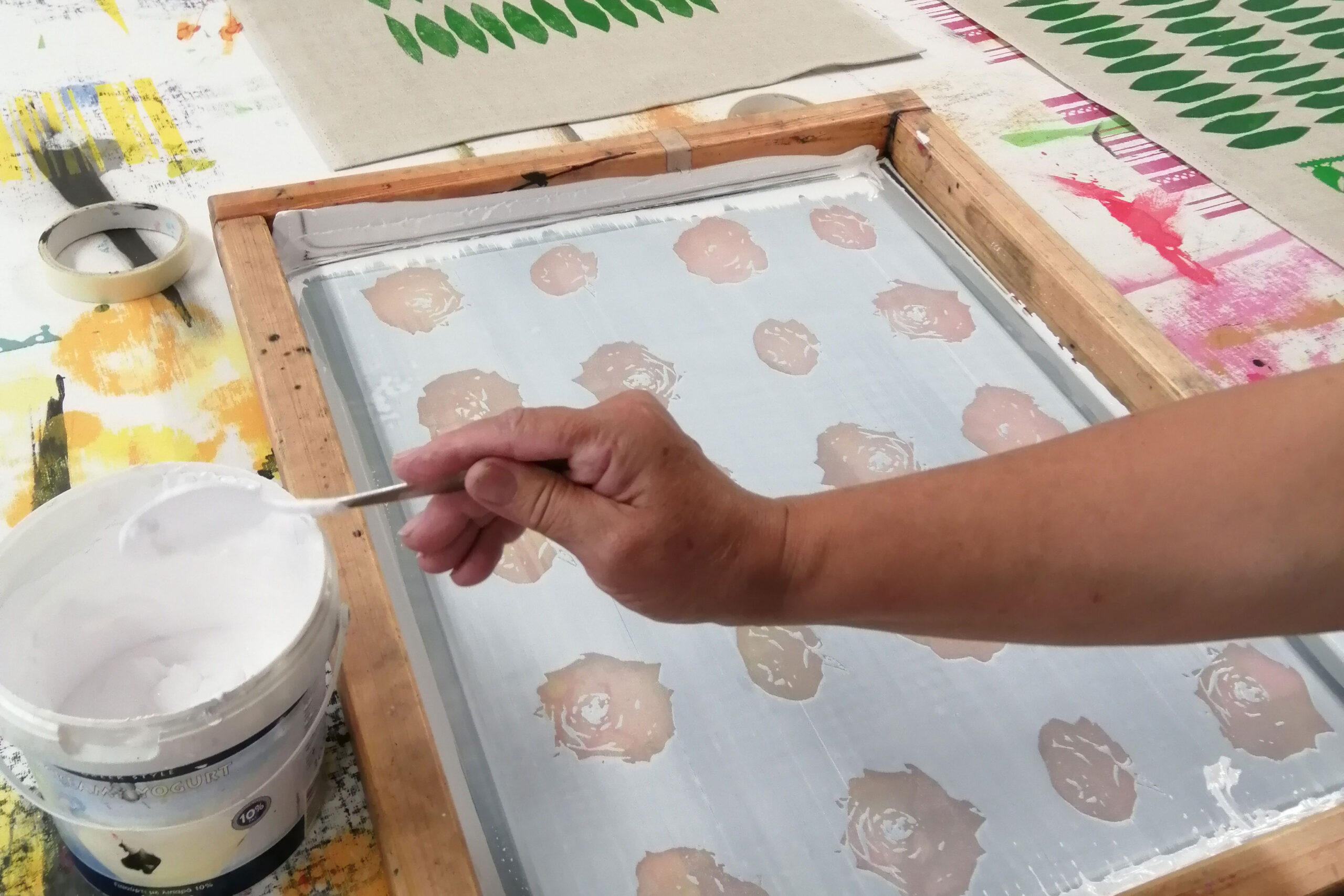Nainen laittaa väriä kankaanpainantaseulalle.